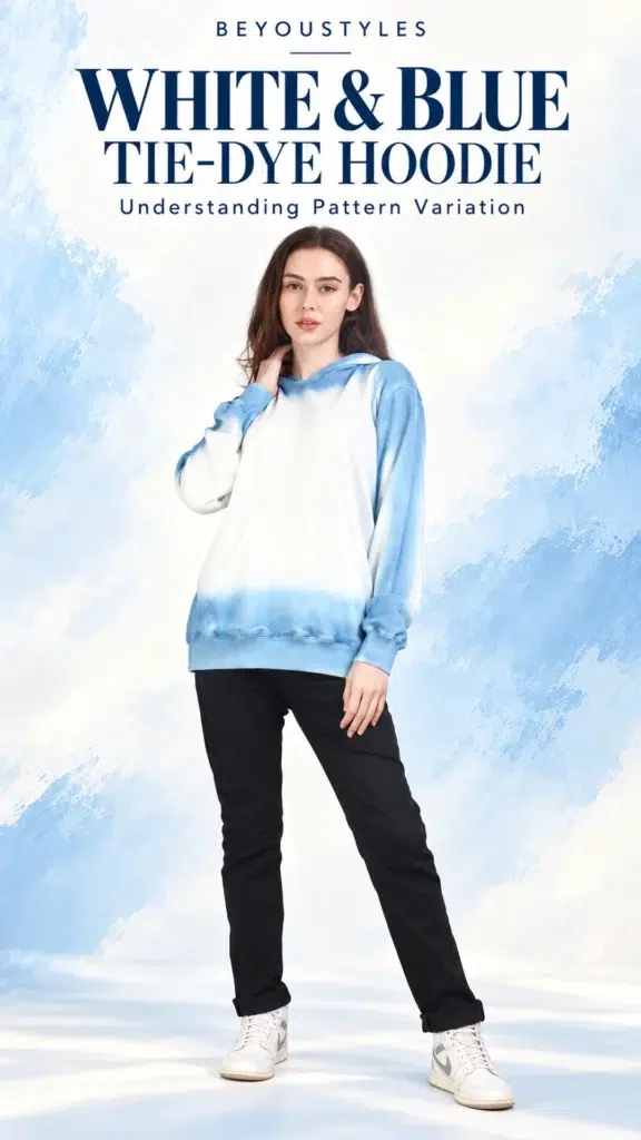 Model wearing a white-and-blue tie-dye hoodie with black trousers against a pale blue background.